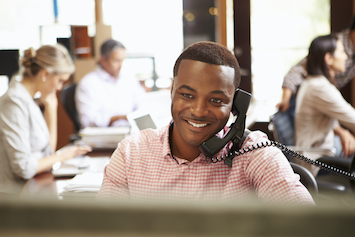 Young man from software support on the phone helping customer