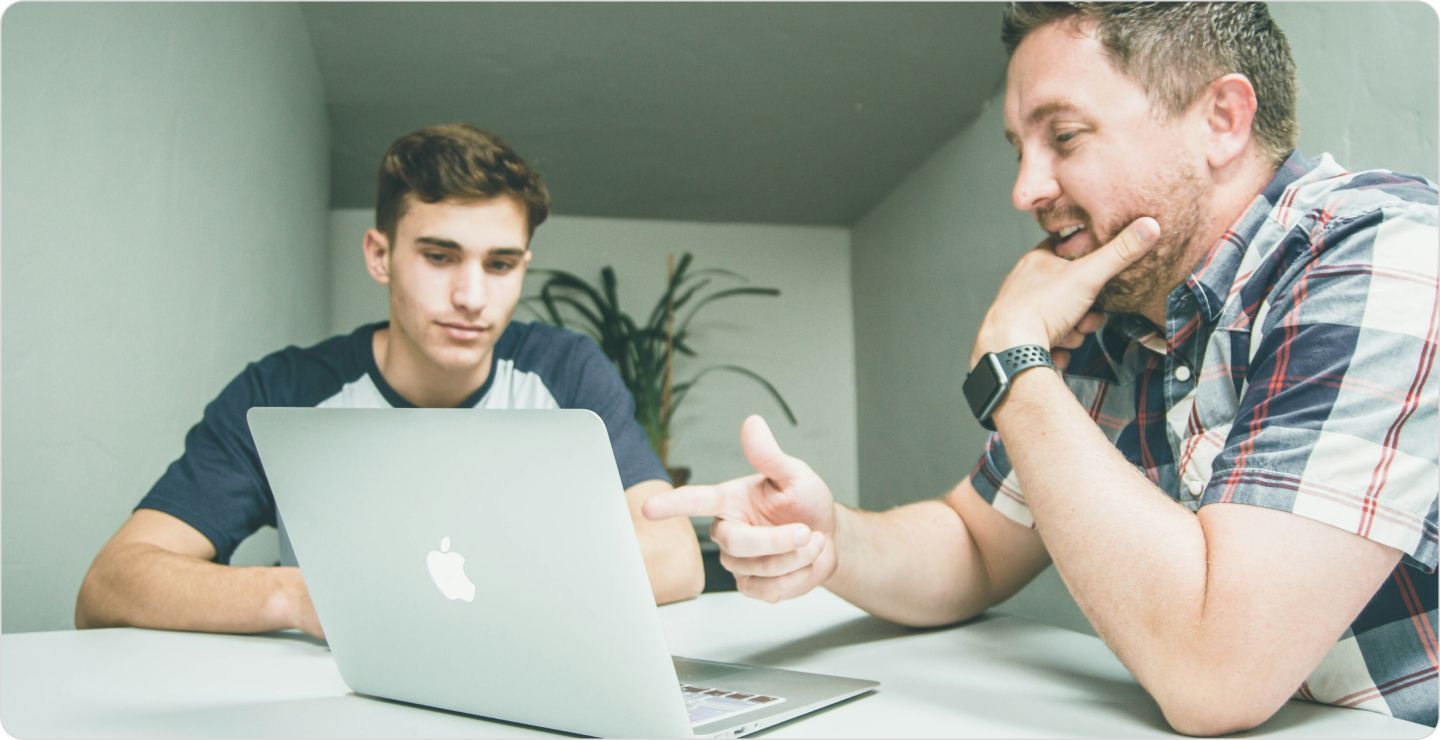 Two men at a desk working on a laptop: illustrating analyzing data for data quality.