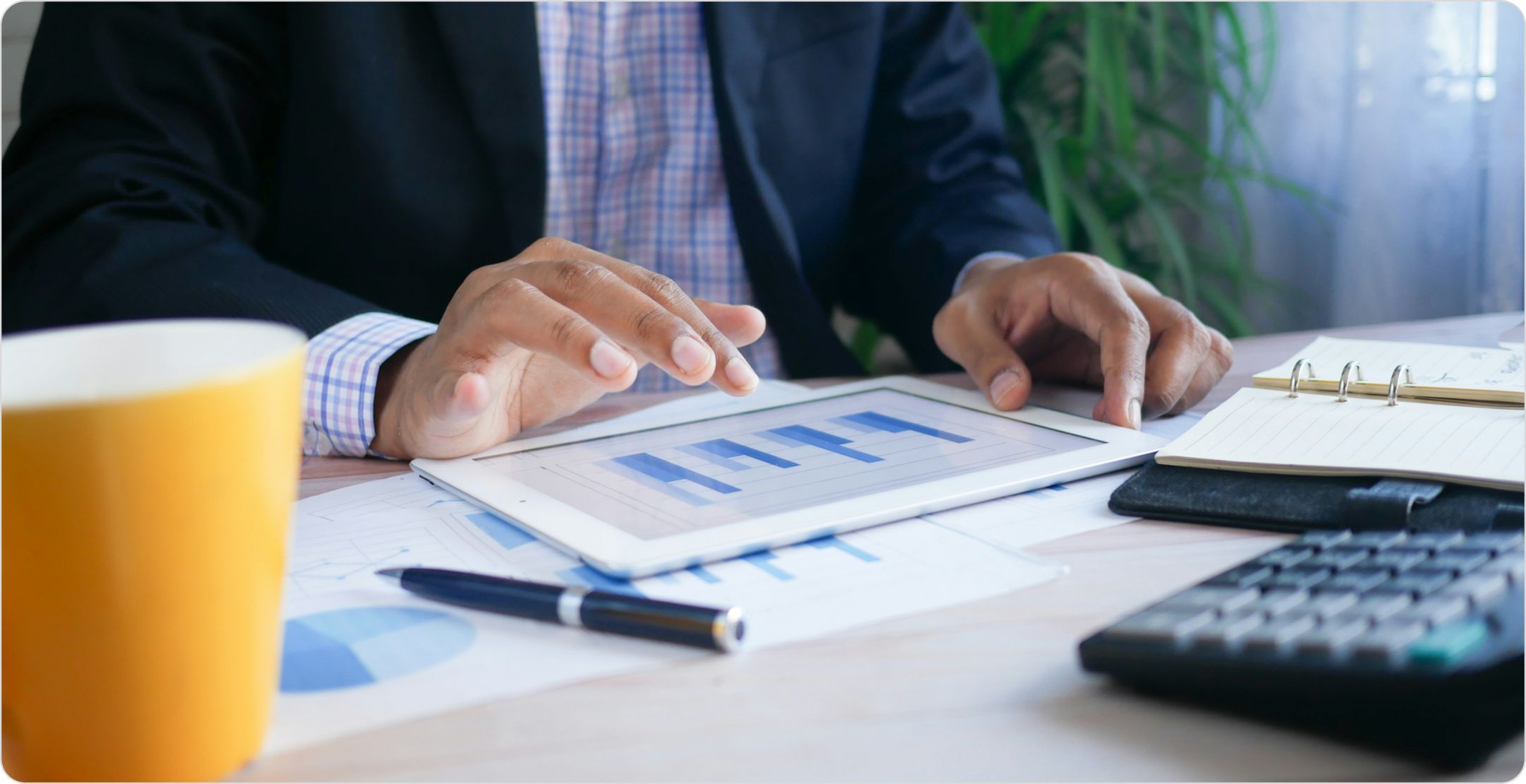 Close up of a man at a desk using a tablet with graphs. Representing data analytics. 