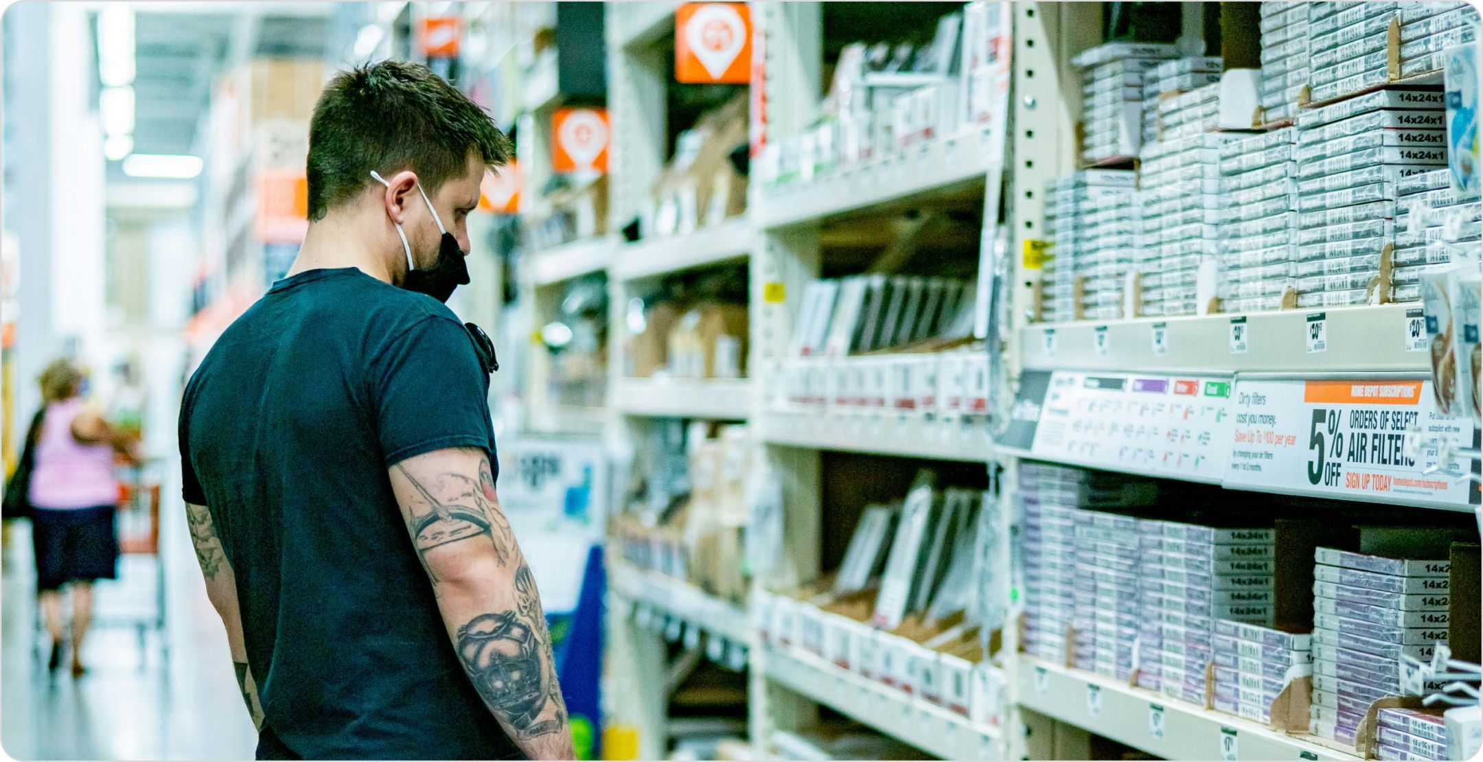 A man looking at a store shelf of hardware products and price tags, symbolizing product pricing.