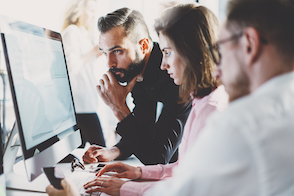 A team of coworkers huddled around a computer