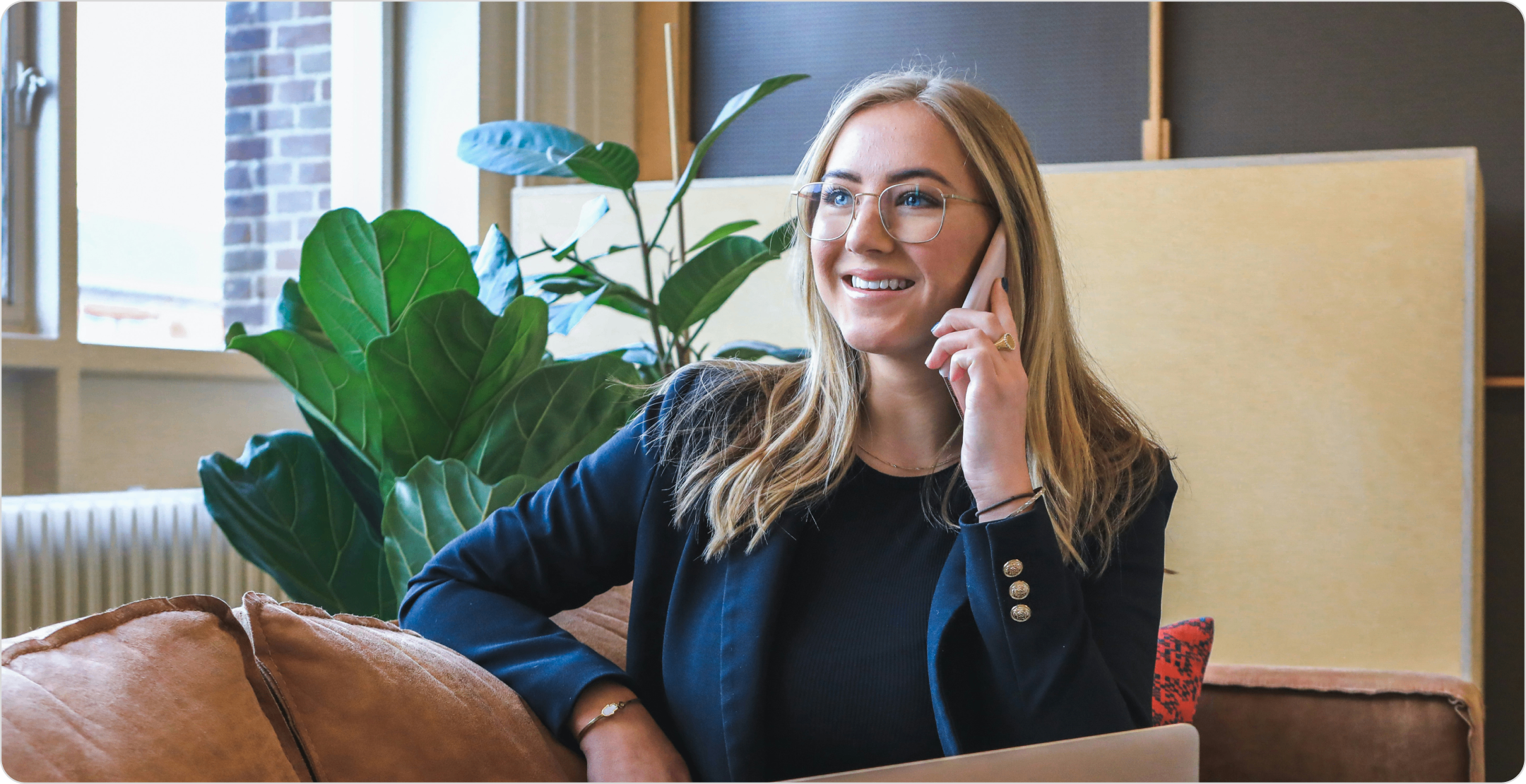 A woman sitting on a couch taking a phone call. Representing phone interviews (one of the survey research types)