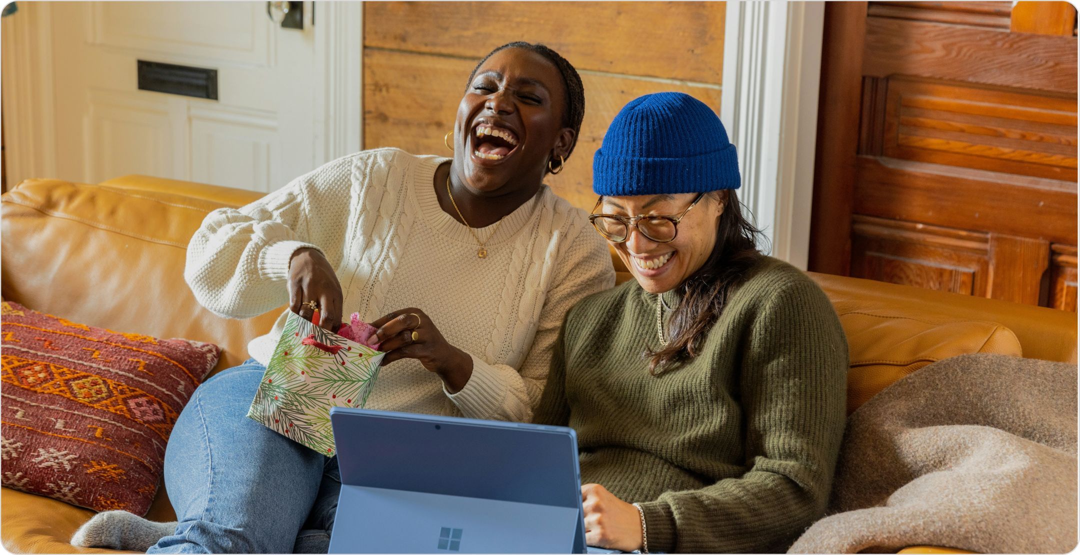 Two women on a couch laughing: representing happy customers from an  NPS survey.