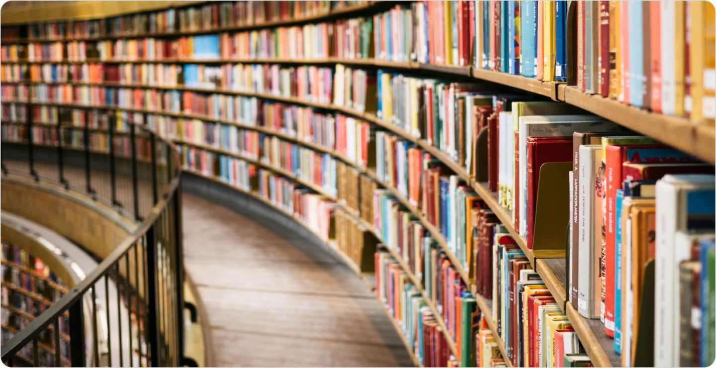 Shelves along the wall of an upper level of a library, representing books as a secondary research source