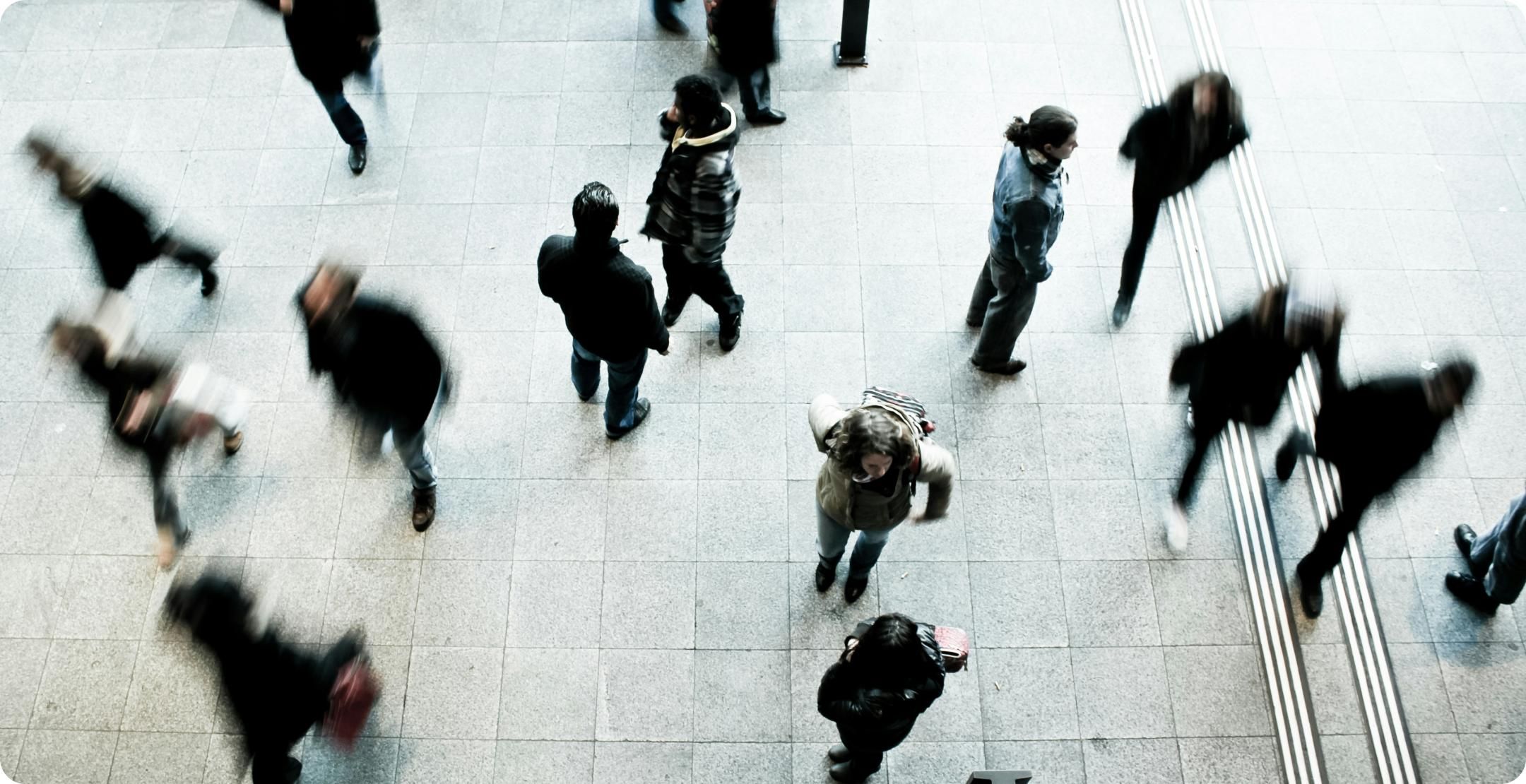 Pedestrians on a footpath. The people walking are blurred while the ones standing still are clear. Represents sample size determination.