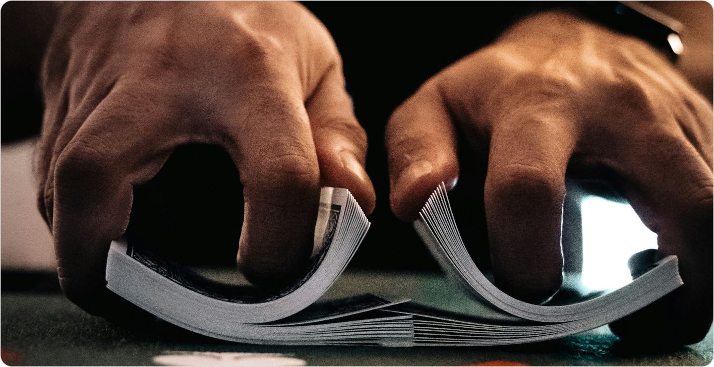 Close up of hands shuffling a deck of cards, illustrating randomized designs.