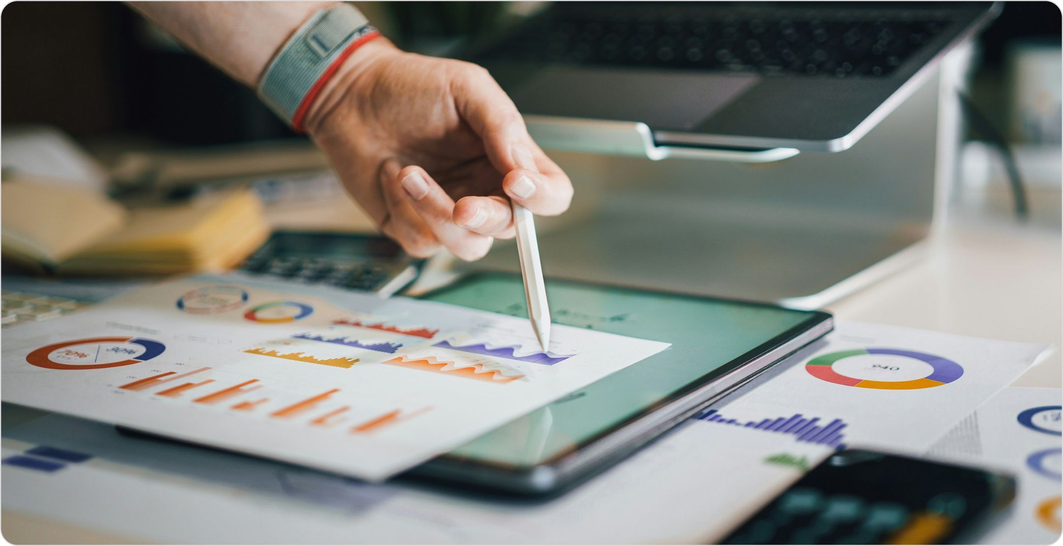 A hand pointing to graphs on a page with a pen; illustrating descriptive analysis.