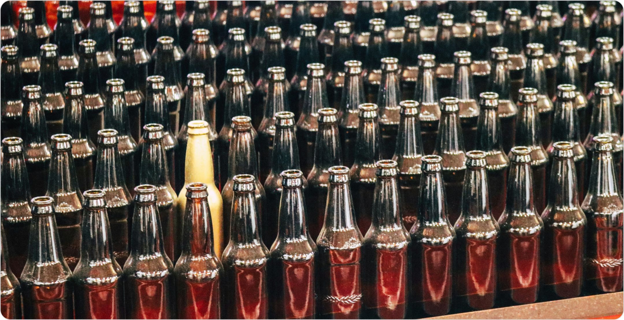 Rows of amber glass bottles with one different cream colored bottle in the middle. Representing selecting sample.