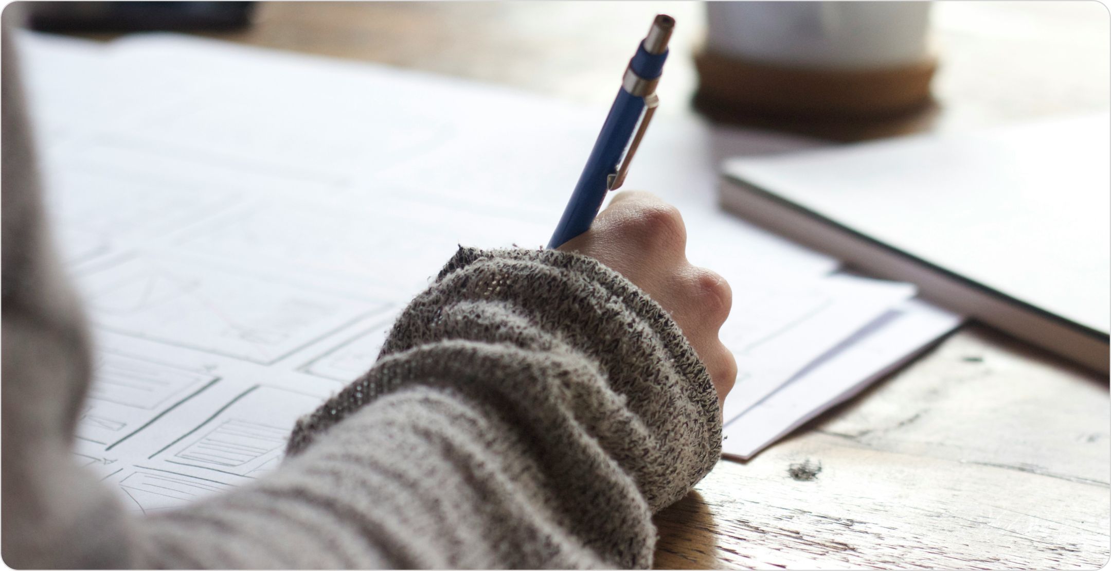 A person writing/drawing frames with varying designs with a pen, representing experimental design in research.